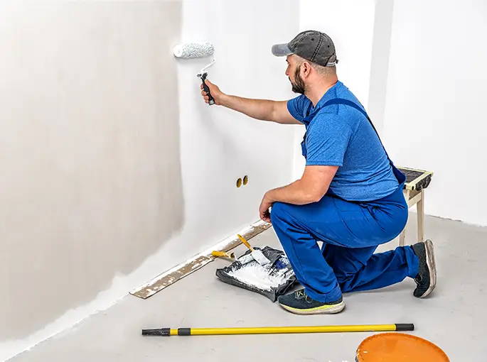 Builder painting the wall with painting roller in white color springfield il