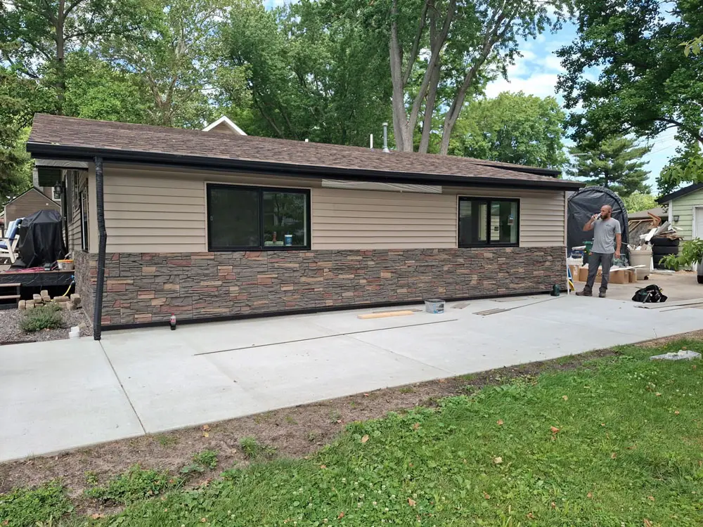 Completed home exterior renovation with new siding, stone veneer, and concrete driveway in Springfield, IL