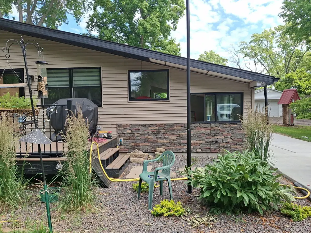 Side view of completed home renovation featuring new siding, stone veneer, and landscaping in Springfield, IL