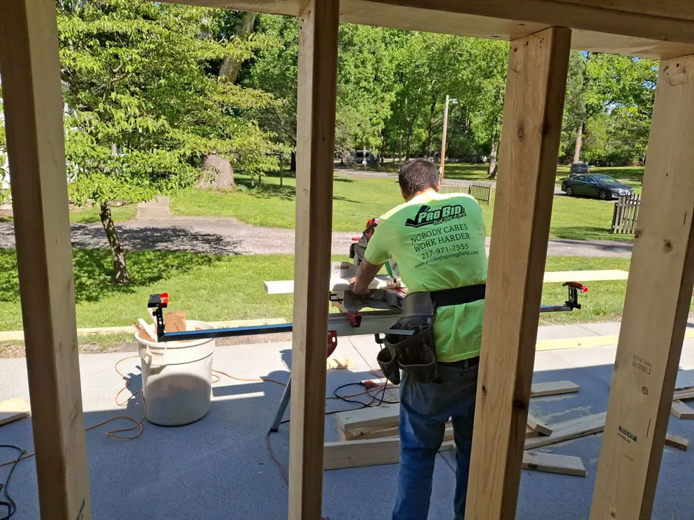 Carpenter measuring and cutting framing lumber for home addition in Springfield, IL